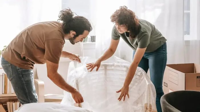A couple covering their furniture to prepare for a storm