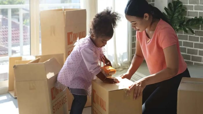 a family packing Mini Mall Storage branded moving boxes