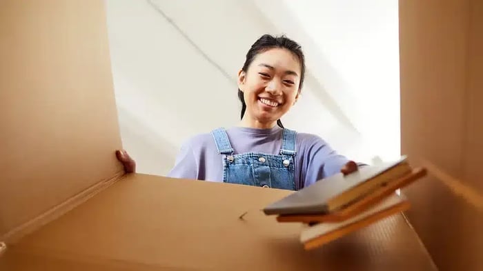 a young woman packs books to be stored