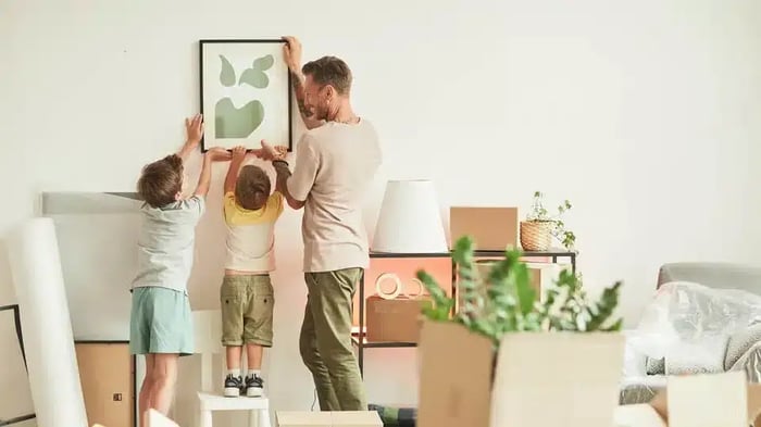 a father and two children get a framed picture ready for storage