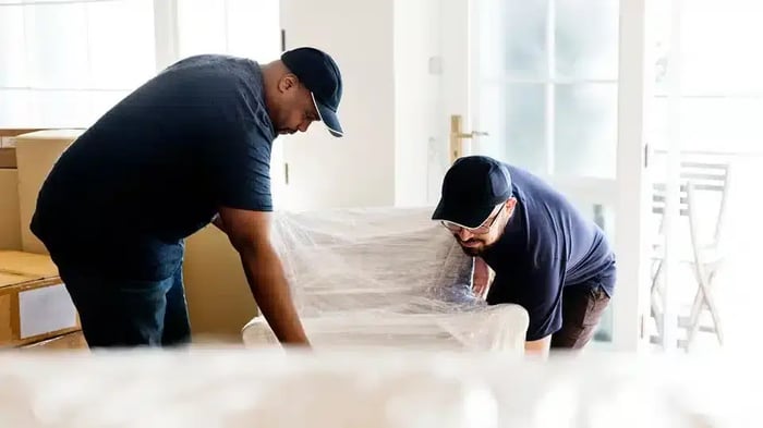 two movers from a moving company moving a piece of furniture to Mini Mall Storage
