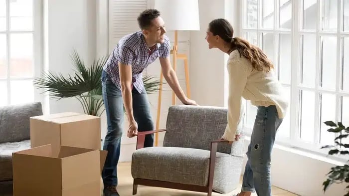 A couple picking up a chair to move to their storage unit
