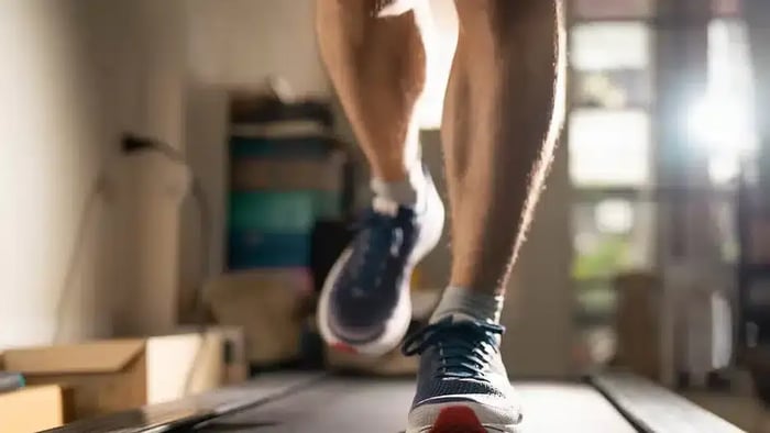 A person running on a treadmill with boxes around him that he got out of his storage unit