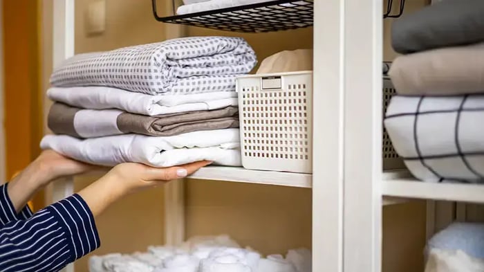 Woman storing towels, bedding, and other linens