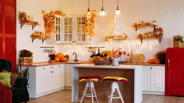 a white kitchen covered in fall decorations and autumn leaves