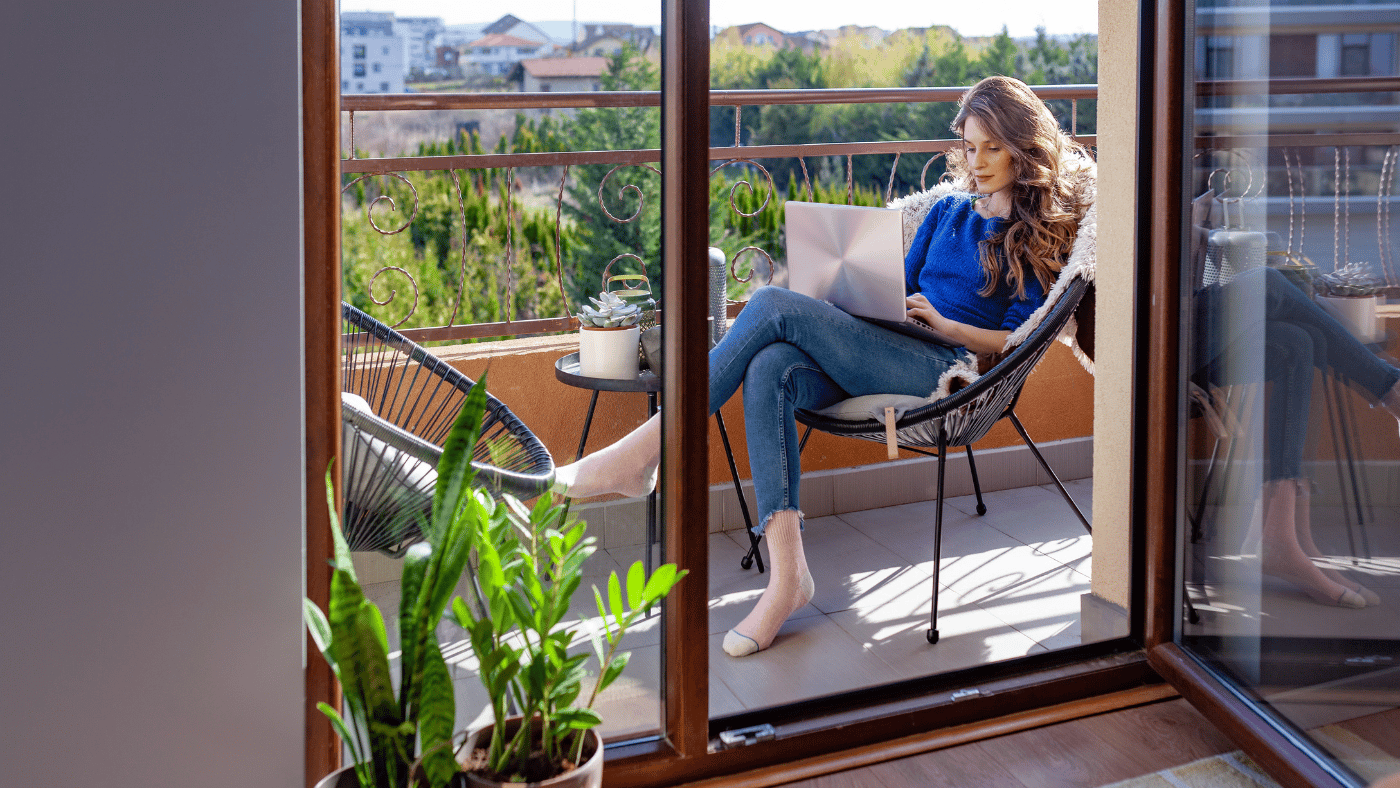 Woman relaxing on a small apartment balcony with compact seating and plants