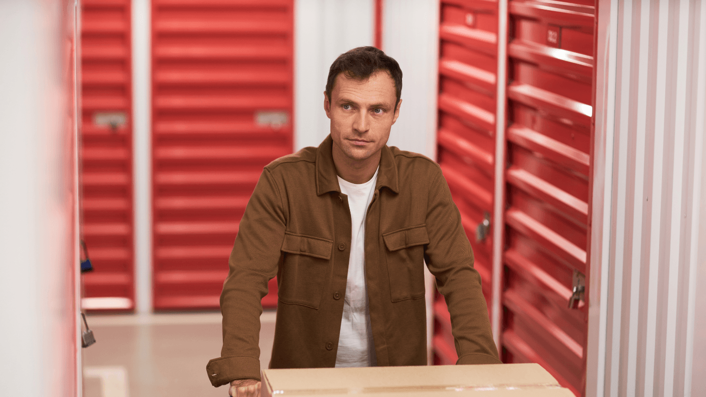 Homeowner carrying a box into a self storage unit to reduce garage clutter